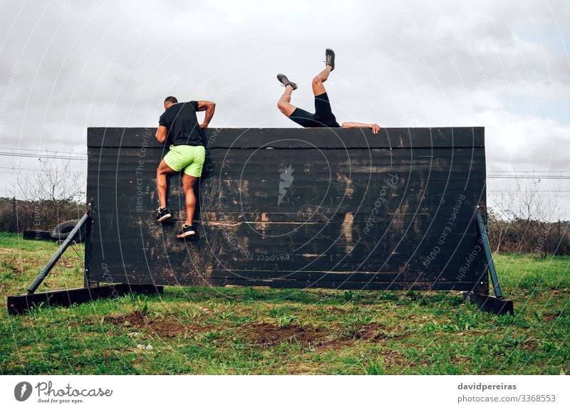Runners in an obstacle course climbing wall Lifestyle Sports Climbing Mountaineering Human being Man Adults Group Jump Authentic Strong Black Effort Competition