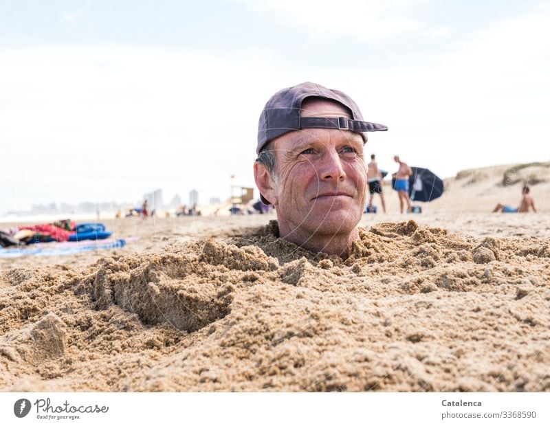 Man with cap sticks head out of sand on beach Colour photo Exterior shot portrait Cap," Blue white background Sky Beach Summer Ocean vacation people bury