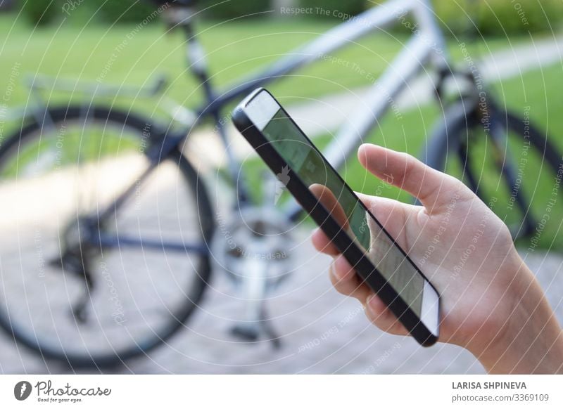 Smartphone in hand woman and blurred bicycle Lifestyle Vacation & Travel Sports Telephone PDA Screen Technology Internet Human being Woman Adults Hand Fingers