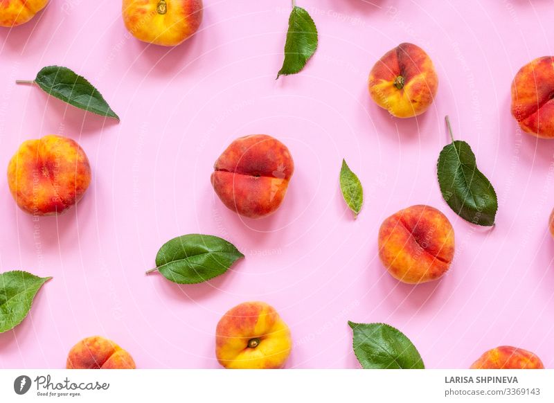 Ripe flat peaches with green leaves on pink background Fruit Dessert Nutrition Vegetarian diet Diet Summer Group Leaf Fresh Delicious Juicy Yellow Green Orange