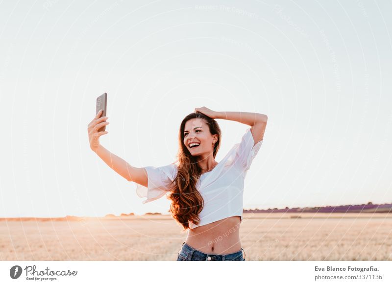 young beautiful woman on countryside at sunset using mobile phone. technology concept portrait outdoors caucasian summer lifestyle happiness smile adult nice