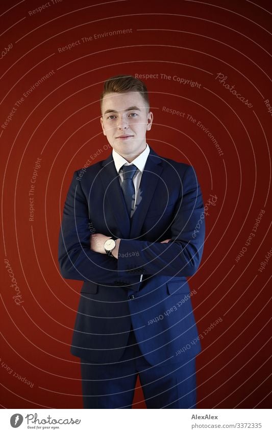 Young man in suit in front of red wall Lifestyle Luxury Style Joy pretty Well-being Office Workshop Youth (Young adults) 18 - 30 years Adults Suit Tie Blonde