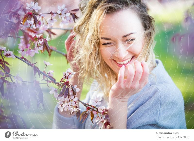 Young woman enjoying the nature in spring. Breathing fresh air and flowers aroma in beautiful park with cherry trees in bloom. Happiness concept Beautiful