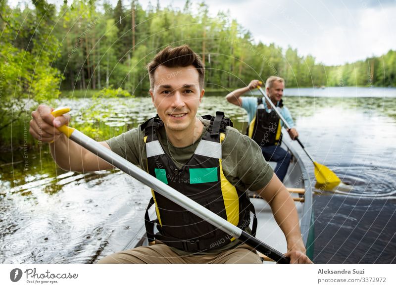 Two men in life vests canoeing in forest lake. Action Adventure candid Canoe Destination Discover Finland Forest Happy Lake Landscape Lifestyle Man Nature