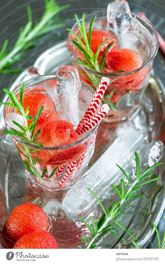 Two glasses of cool refreshment with watermelon, rosemary and ice sticks on a silver tray Water melon Cold drink Fruit Rosemary Beverage Drinking water Glass