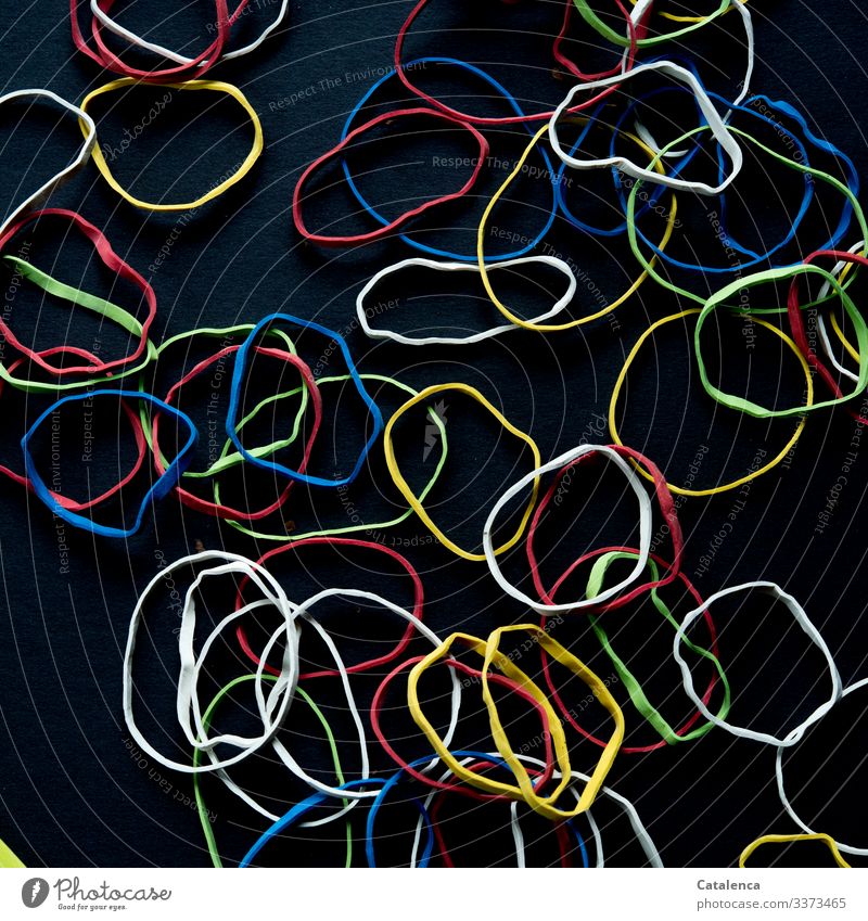 Challenge |Colorful rubber bands lie scattered on black background Elastic band Dark Multicoloured Black Adaptable Colour Environmental pollution Close-up