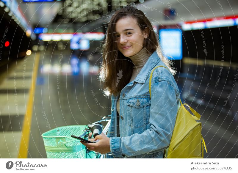 Teenager girl with backpack and bike on metro station Action Bicycle Cycling Easygoing Casual clothes Friendliness Cheerful City Destination Ecological Finland