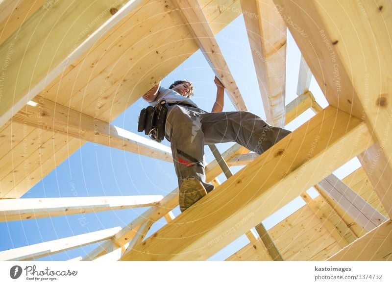 Builders at work with wooden roof construction. house frame home builder carpenter roofer worker lumber building development tool workman timber hardhat