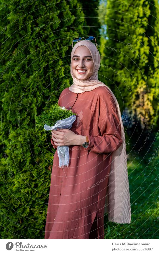Muslim woman in hijab smiling  with flowers bouquet muslim religion smile portrait beautiful beige bright cheerful close up clothing confident dress elegant