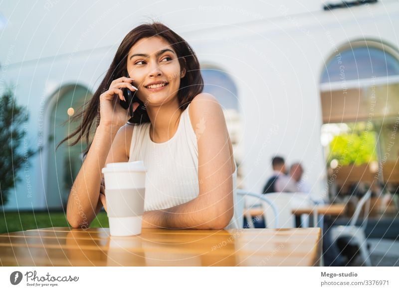Young latin woman talking on the phone. happy mobile girl outdoor call smart cell pretty young coffee shop smartphone cellphone conversation urban people