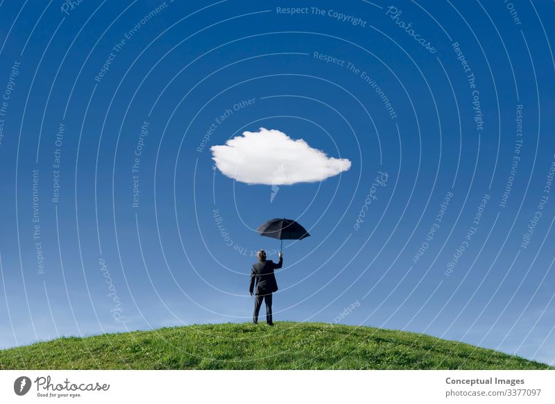 Businessman holding umbrella underneath a single cloud Clouds Grass Hill Stand Anticipation Protection Loneliness Serene Forecasting Hold Non urban scene