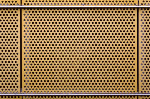 perforated sheet Metal Yellow Tin Plate with holes Wall cladding Hollow Deserted Copy Space Colour photo Exterior shot Day