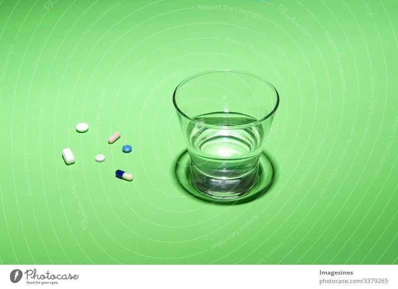 Glass of water and vitamins, pills and tablets on green background with text Free space Water Green Text Free Space antibiotic aspirin Capsule Close-up concept