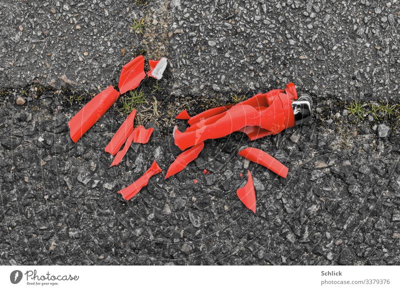 Broken red disposable lighter on asphalt disintegrates into microplastic Environment Lighter Metal Plastic Gray Red Black Silver Environmental pollution