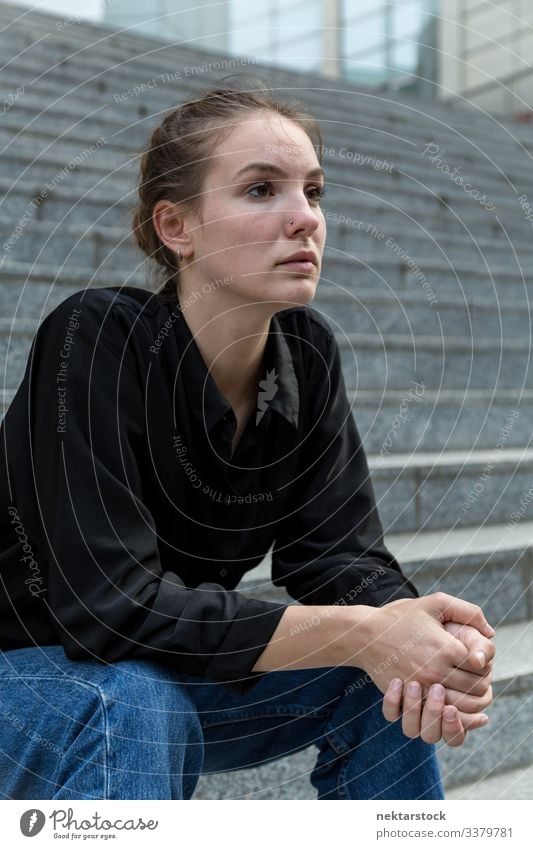 Side View Portrait of Young Caucasian Woman Sitting on Outdoor Steps sitting female girl woman steps marble stone looking away serious strong attitude