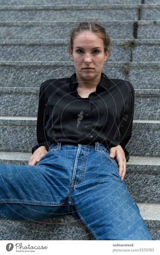 Young Woman Seated Leisurely on Outdoor Steps Looking at Camera sitting back female girl woman steps marble stone looking at camera at ease leaning back serious