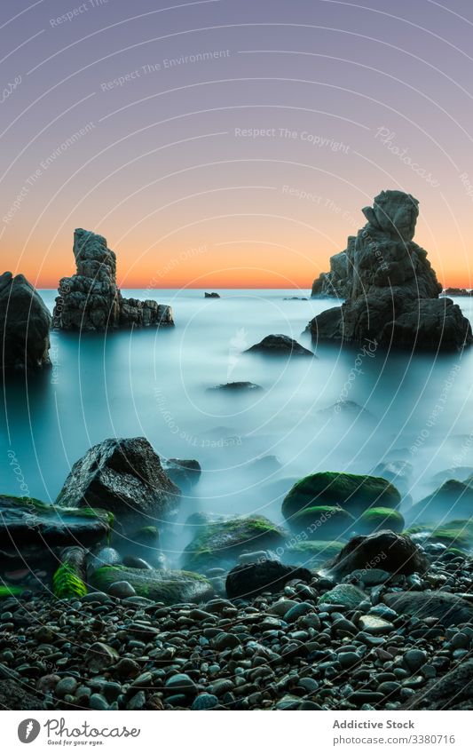 Amazing sunset above rocky seashore in mist landscape long exposure sky nature colorful blue turquoise cliff marine beach water stone scenic tranquil coast