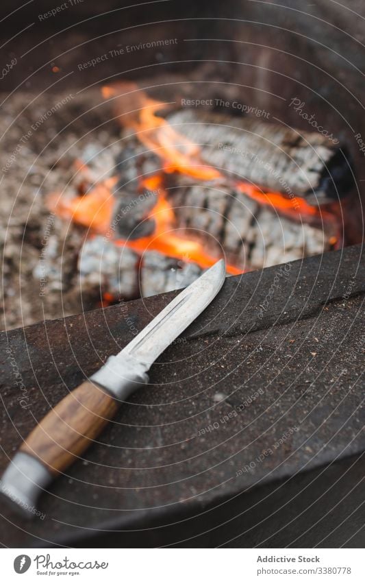 Hunting knife next to fireplace bonfire flame heat burn hot hunt wooden firewood tool steel instrument iron light nobody orange concept utensil craft handle