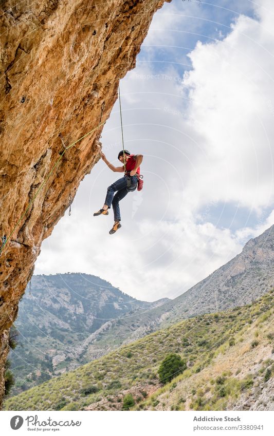 Courageous female climber hanging on cliff woman alpinist ascend mountain terrain adventure extreme risk challenge adrenalin freedom altitude rope journey sport