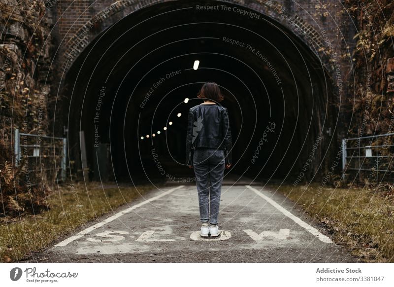 Woman standing in front of dark tunnel on road woman illumination inscription slow travel architecture building old walk street stone path ancient tourist