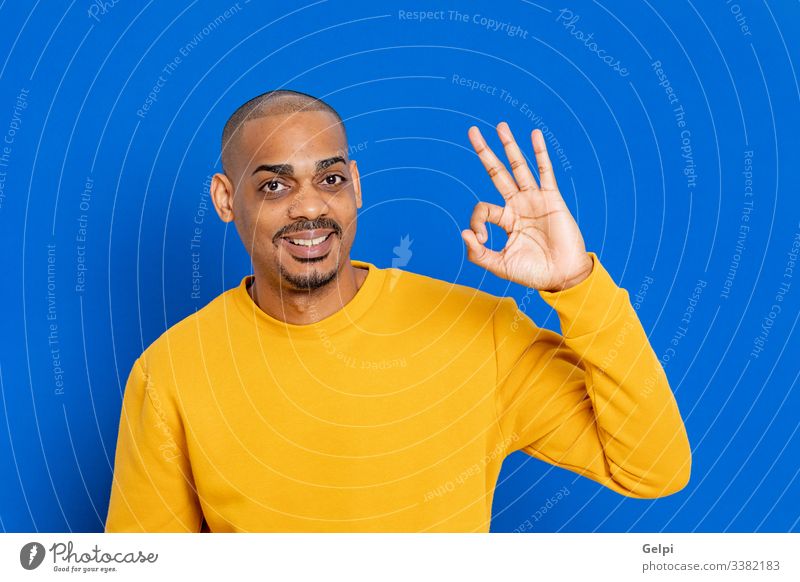 African guy with a yellow jersey black blue Ok accept yes happy smile funny sigh finger hand adult people person african male american man isolated background