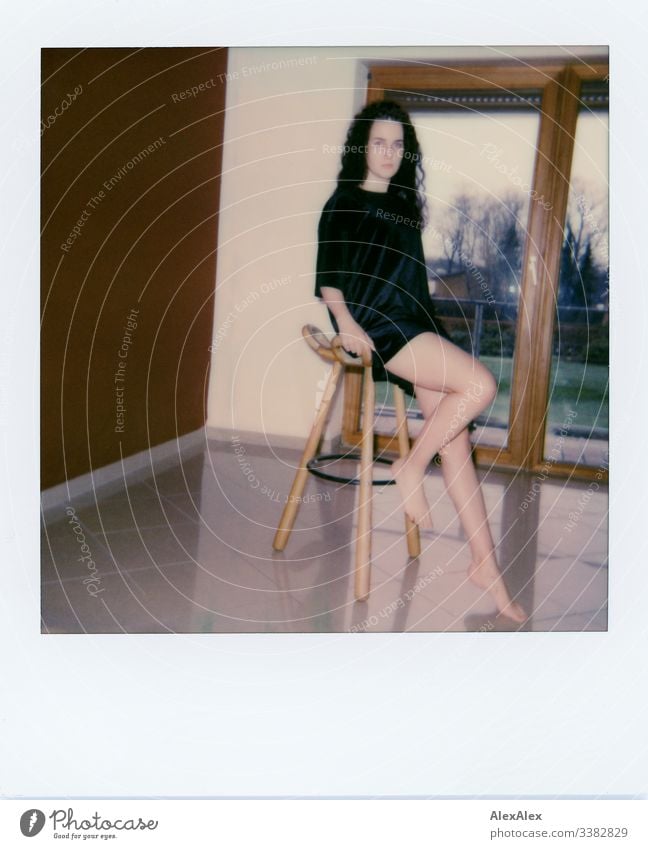 Analog Polaroid portrait of a young woman in front of a balcony window Looking into the camera Portrait photograph Central perspective Shallow depth of field