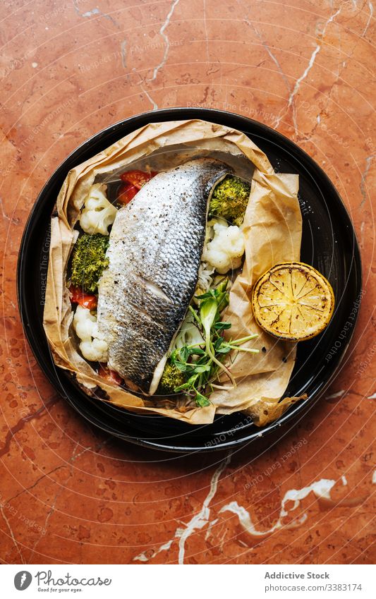 Tasty baked dish of fish and vegetables in restaurant haute cuisine lemon broccoli cauliflower herb plate seafood delicious meal tasty appetizing dorado portion