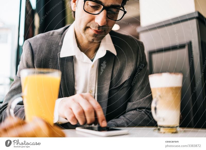 Businessman at the bar having a cup of coffee and orange juice adult application breakfast business businessman cafe cheerful communication drinking executive