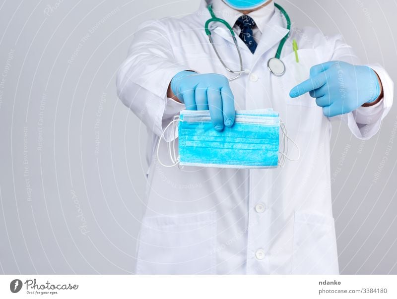 doctor in a white coat, blue latex sterile gloves holds textile medical masks in his hand, protective accessory against viruses medicine nurse occupation