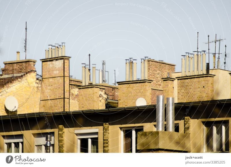 Collection of chimneys and a few antennas Side by side Roof Chimney Symmetry Nostalgia Cloudless sky Window Above Sunlight Neutral Background apartment building