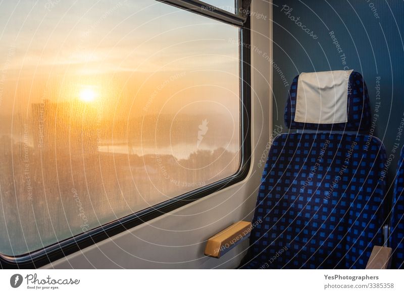 Train interior with chair and sunrise view on window. Train travel German train Germany blue chair carriage comfortable commute eco-friendly empty chair
