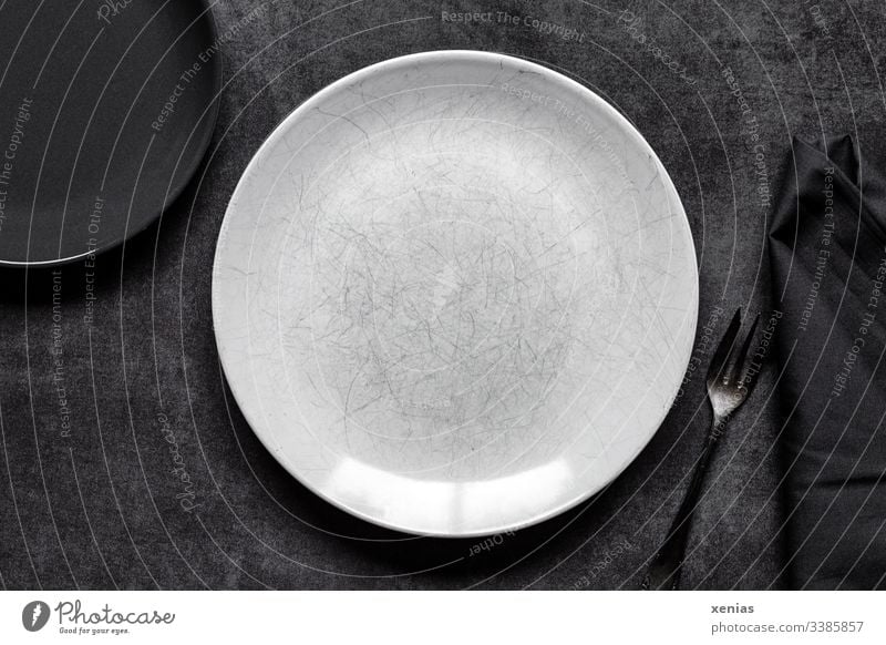 Light and dark round plate with fork on grey background Plate Empty Food photograph Round White Interior shot Nutrition Fork Napkin Table Black scratched Eating