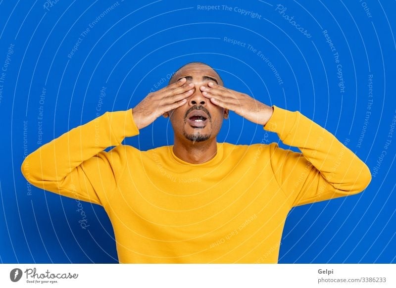 African guy with a yellow jersey black surprised exciting crazy happy emotion cover eyes blind closed blue adult people person african male american man