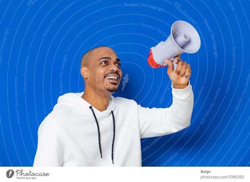 African guy wearing a white sweatshirt black blue megaphone loudspeaker yelling shout announce voice shouting communicate announcement ad advertisement adult