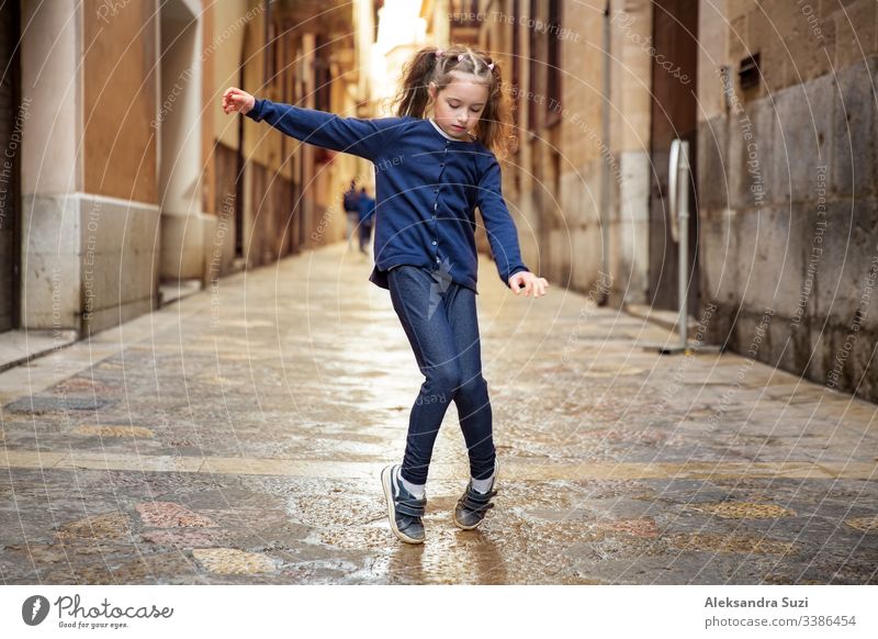 Cute little girl dancing on city street. Narrow streets of Palma de Mallorca old town. active beautiful carefree child childhood children concept cool dance