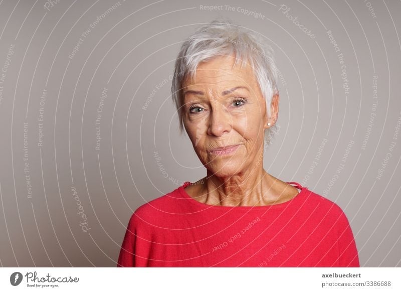 mature woman with skeptical look on her face serious senior lady adult 60 sixties older person sceptic sceptical earnest female people elderly grey gray