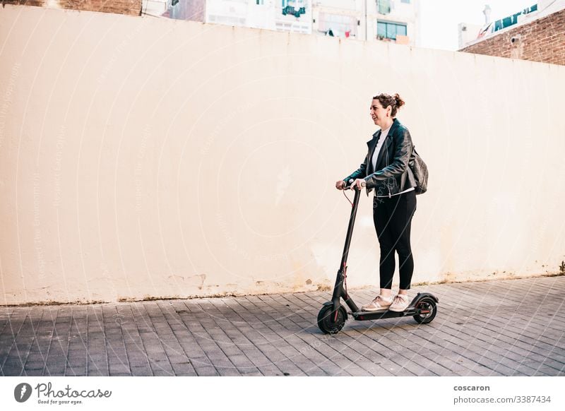 Middle aged woman riding an electric scooter active adult alone attractive background board business cheerful city driving e scooter eco electrical equipment