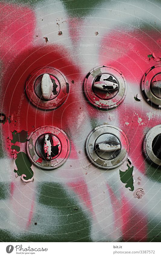 symmetry l old, sprayed, round rotary switches in an empty factory. Wall with graffiti in pink & green painted with light switches. Many, old, broken, painted, nostalgic building services, lighting system, switchgear with round rotary switches. Lost Place.