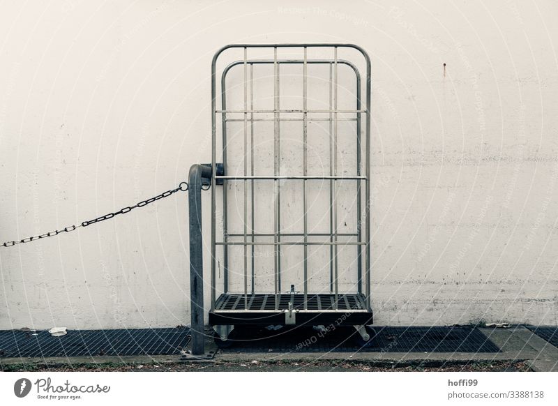 empty trolley with chain and steel tube Delivery truck Chain Gray Gloomy dreariness urban Exterior shot Deserted white wall Wall (building) dirt off-white