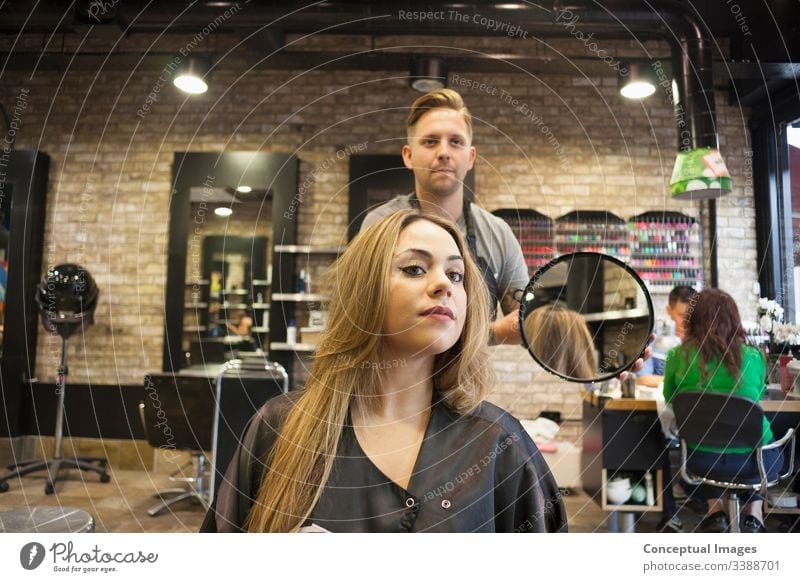 Caucasian woman having her hair styled in a hipster barbershop themes of hairstylist pampering glamour haircare haircut salon hairdressing hairdresser hairstyle