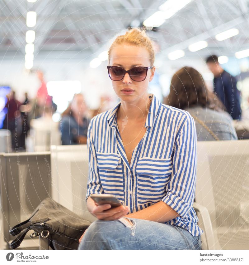 Woman using her cell phone while waiting to board a plane at departure gates at international airport. woman travel sitting ticket beautiful passenger female