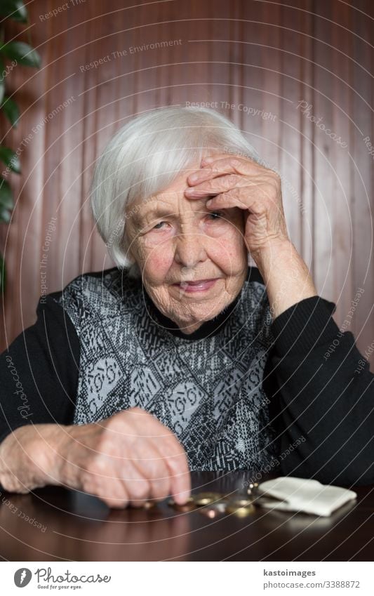 Elderly woman sitting at the table counting money in her wallet. senior pensioner elderly poverty retirement old empty coins background miserable broke lonely