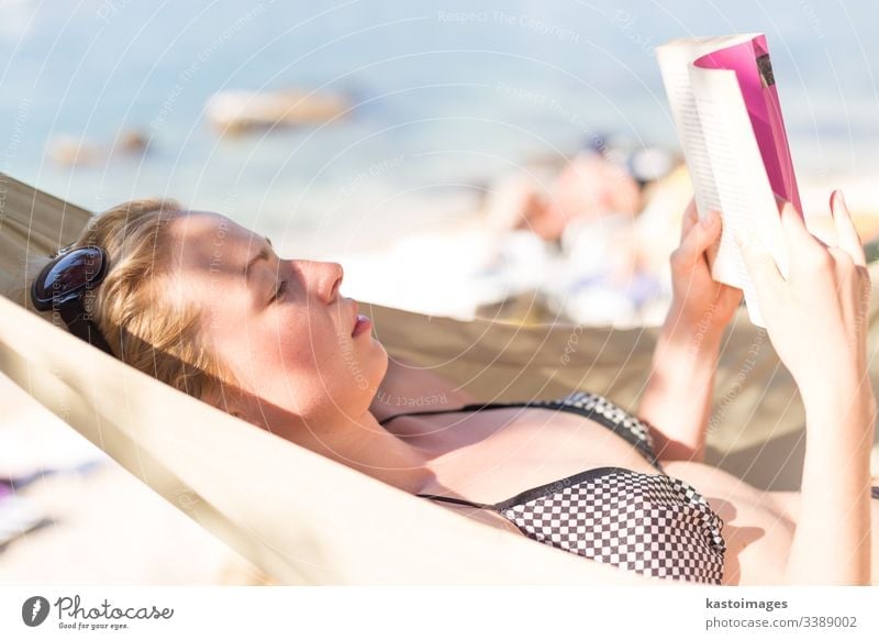 Woman reading book in hammock on the beach vacation day female woman relax young novel relaxation rest summer leisure lying human idyllic person resort relaxing