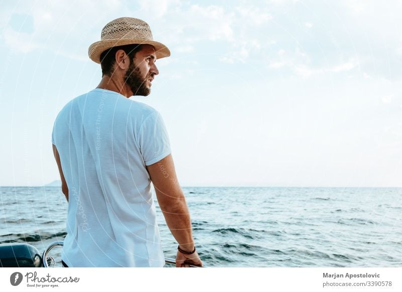 Young man enjoying a ride on a boat on the sea young handsome bearded casual adventure ocean water waves cruise speedbo nautical male summer vacation holiday