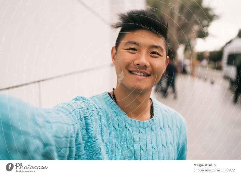 Asian man taking a selfie. confident looking guy asian background smile men face urban city life profile cheerful picture front photography holding street
