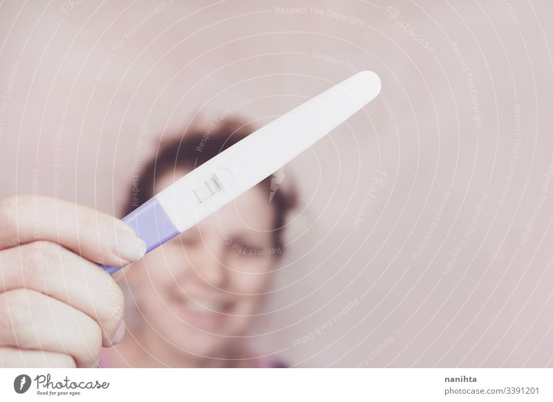 Young happy woman holding a positive pregnancy test pregnant mom mother family happiness mood emotion emotive optimism femininity feminine pink growth life