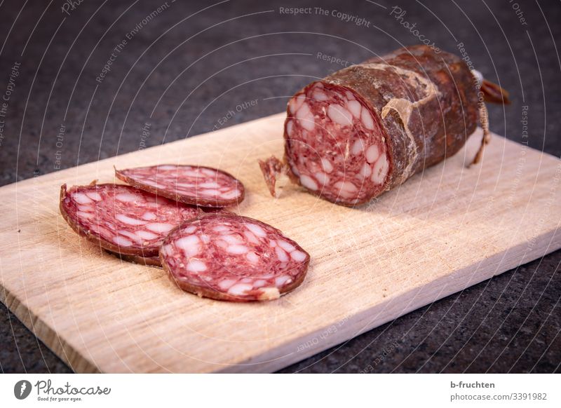 Raw sausage cut into slices on a wooden board Sausage snack time Wooden board Snack board Break Unhealthy Fat Salami Fresh Eating Deserted Food Meat Close-up