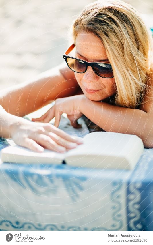 Young woman reading a book lying on the beach attractive beautiful beauty bed blonde casual caucasian closeup cute day enjoy female freckles girl hairstyle
