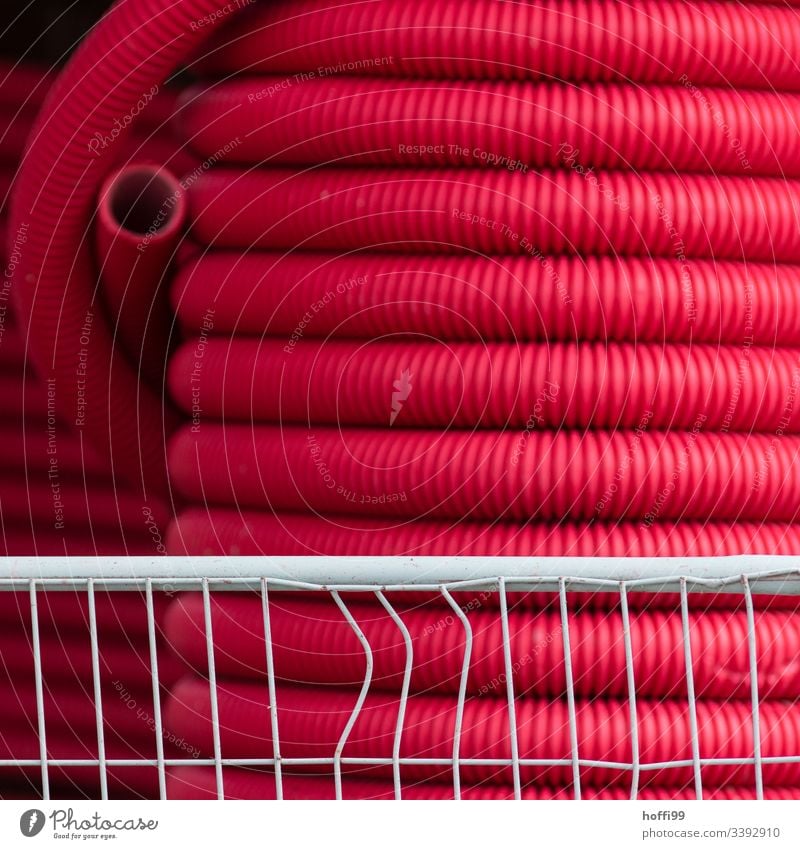 large roll with red flex hose behind a deformed barrier Red hoses Irrigation Housing PVC Pipe Effluent Sewer Construction Telecommunications Plastic Coil