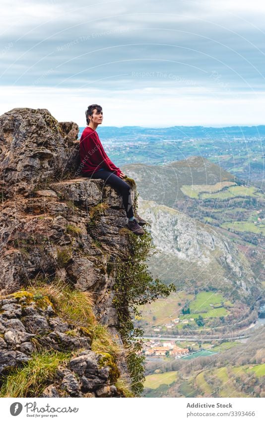 Traveler enjoying landscape while sitting on edge of rock against misty highland traveler cliff mountain trekking viewpoint freedom height adventure relax